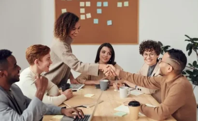 A group of people shaking hands at a meeting, symbolizing collaboration and agreement.