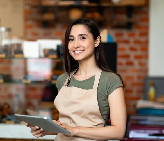 Woman smiling while holding tablet in coffee shop.